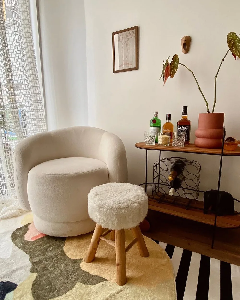 Canto de leitura com poltrona bouclé, aparador e objetos garimpados